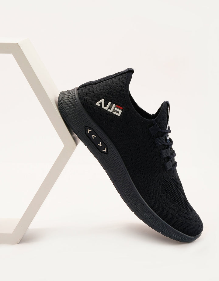 A black running sneaker with lace-up closure, featuring a textured upper and a flat sole.